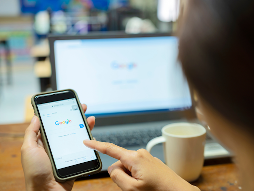 Business owner optimizing Google Business Profile settings on a laptop, showing increased local search visibility and customer traffic metrics in the dashboard.